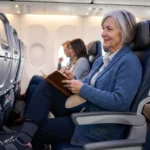 Older woman with neuropathy sitting comfortably in airplane aisle seat wearing compression socks