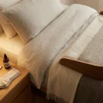Neat bedroom with bed cradle, folded merino socks, thermometer, and moisturizer on the nightstand at bedtime