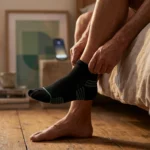 Older adult pulling on a smart sock with foot temperature sensors to monitor for diabetic neuropathy hot spots.