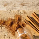 Ground cinnamon and whole cinnamon sticks on a wooden board in hard side light