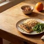 Simple home-cooked meal of fish, rice and vegetables on a wooden table