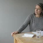 Woman at kitchen counter looking at a wall calendar marked across many weeks