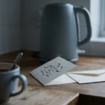 An unanswered invitation propped against a kettle beside a half-drunk mug of tea