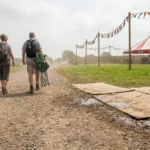 Path into a county fair changing from gravel to grass to plywood with tents ahead