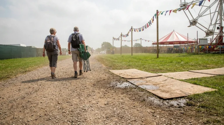 Path into a county fair changing from gravel to grass to plywood with tents ahead