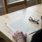 Clinic letter lying on a kitchen table beside reading glasses and a cup of coffee