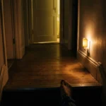 Dim hallway at night lit by a low amber night light near the floor