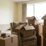 Half-packed living room with small cardboard boxes and an armchair in daylight