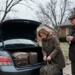 Older couple loading suitcases into a car trunk in a driveway on an overcast autumn day